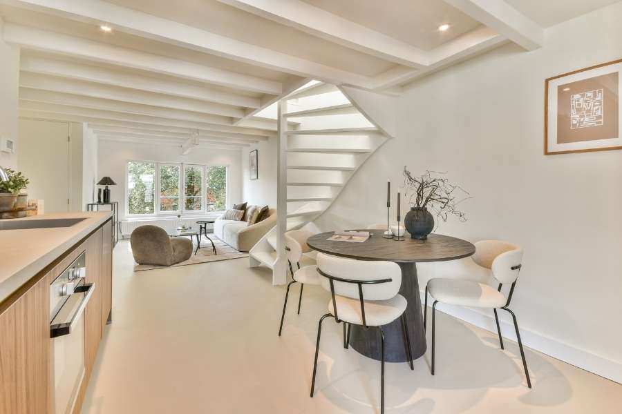 Un intérieur ouvert avec escalier blanc et coin repas pour aménager un petit espace de manière élégante.