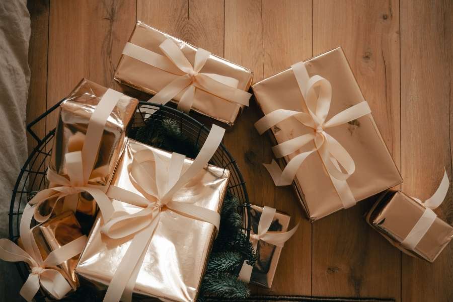Couronne de Noël décorée avec des cadeaux d'entreprise emballés dans du papier doré et rubans satinés