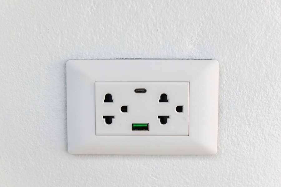 Des prises USB murales modernes avec ports USB-C et USB-A intégrés sur un mur blanc.