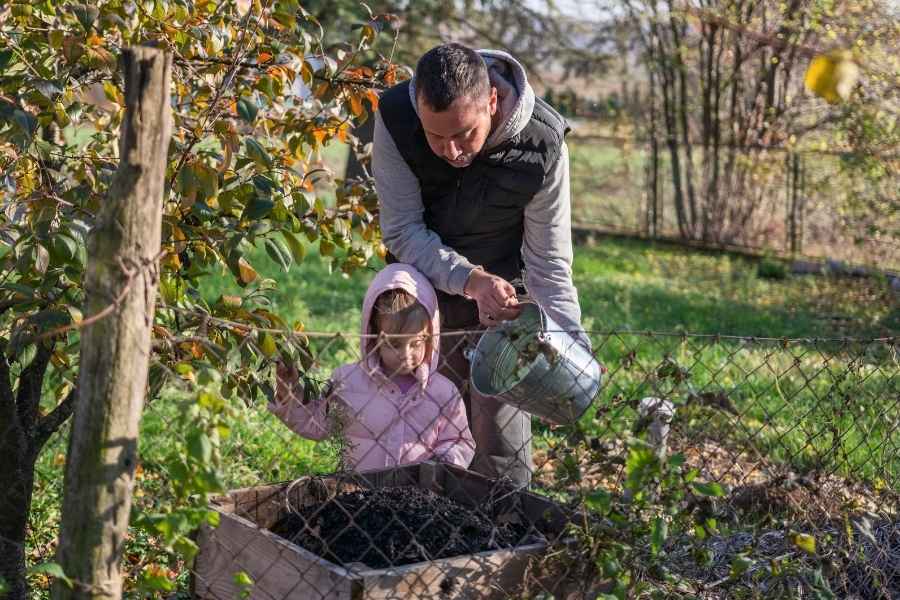 Père et fille pratiquant le compostage domestique ensemble dans un jardin familial en automne