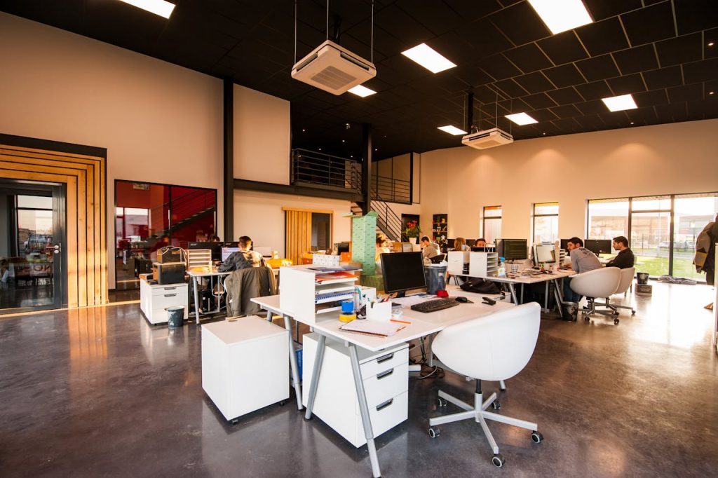 Vue d'un bureau open-space moderne et lumineux au Maroc, où plusieurs professionnels travaillent devant leurs ordinateurs, illustrant les infrastructures pour digitaliser son business Maroc IA.
