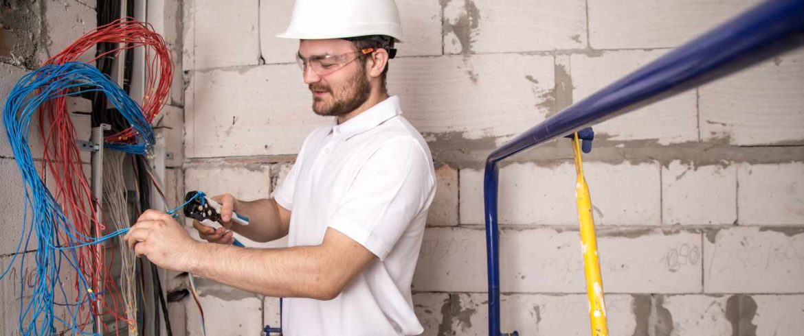 Électricien raccordant des câbles dans un tableau pour la préparation chantier rénovation électrique.